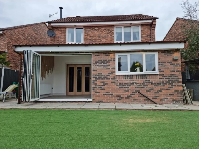 Brick rear extension with bifold doors opening onto a lawn